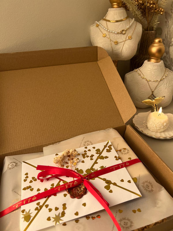 Gift box with a red ribbon on a decorative table with mannequin heads and candles.