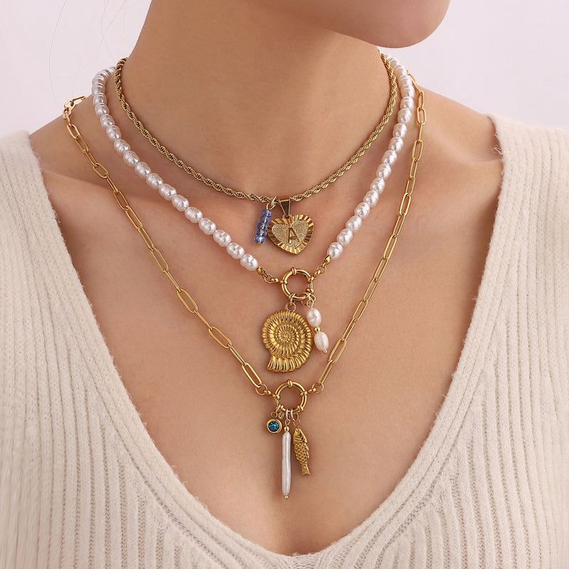 Necklace with pearls and charms on a person wearing a beige sweater