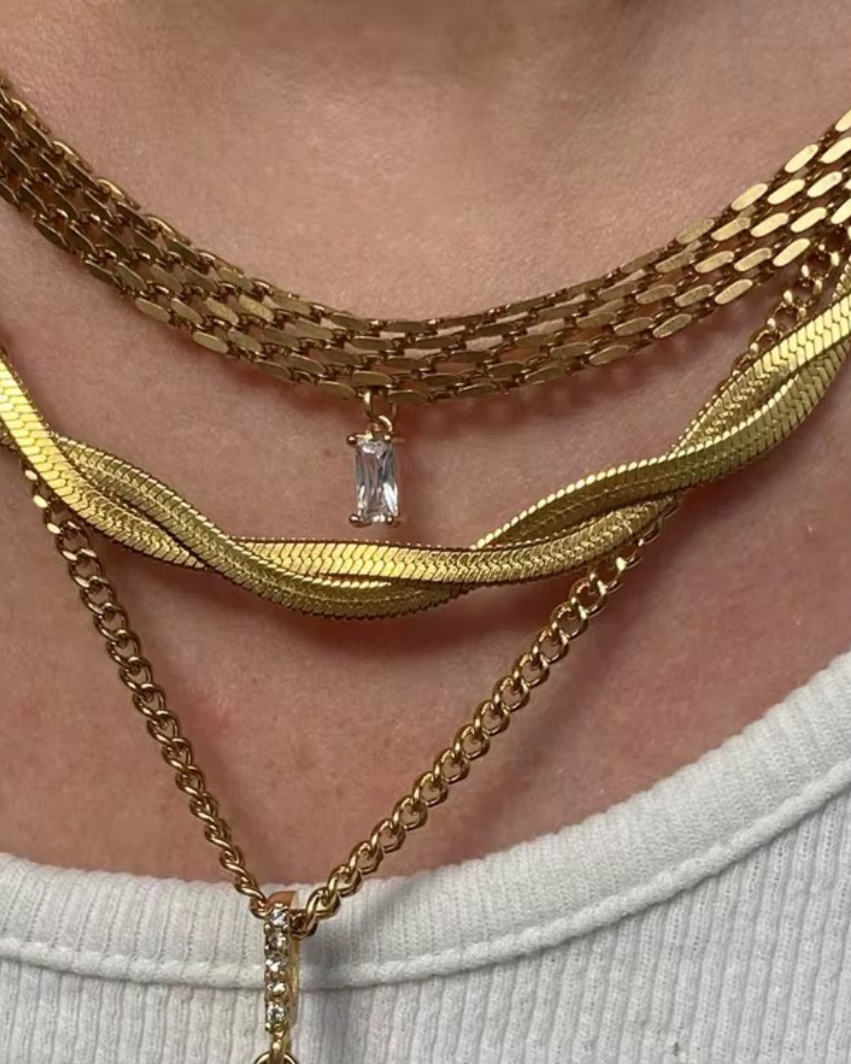 Close-up of a person wearing multiple gold necklaces with a clear pendant.