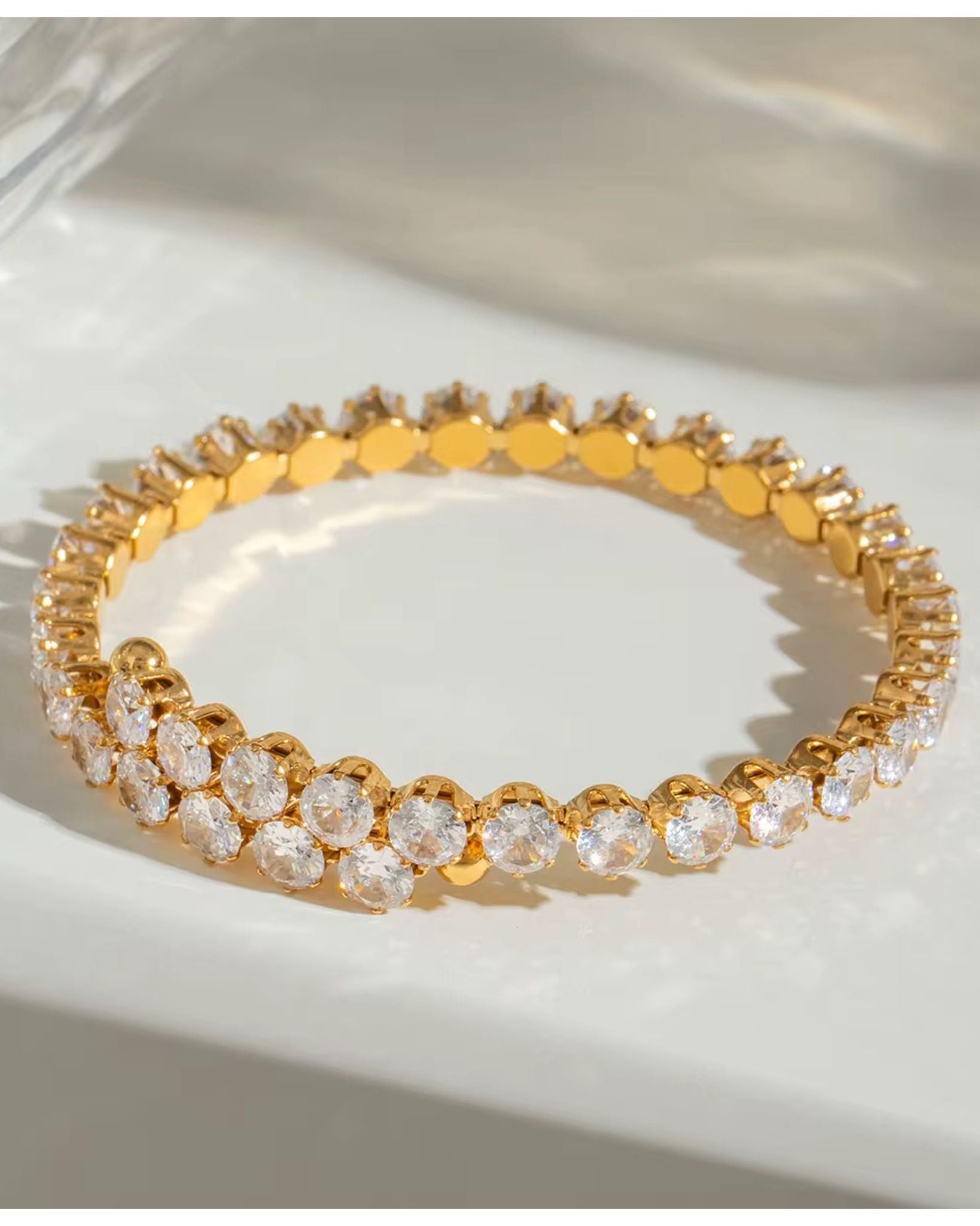 Gold amiri zircon bracelet with clear stones on a white surface