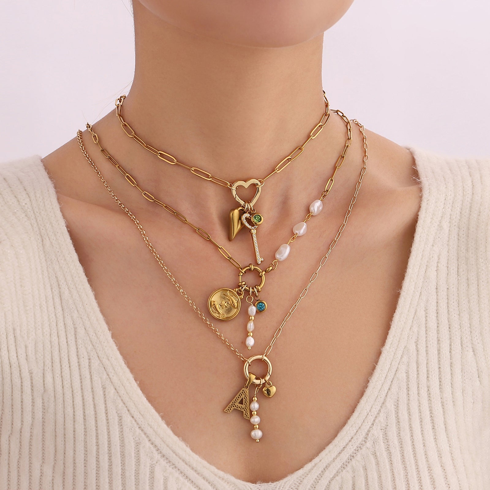 Gold necklaces with charms on a plain background