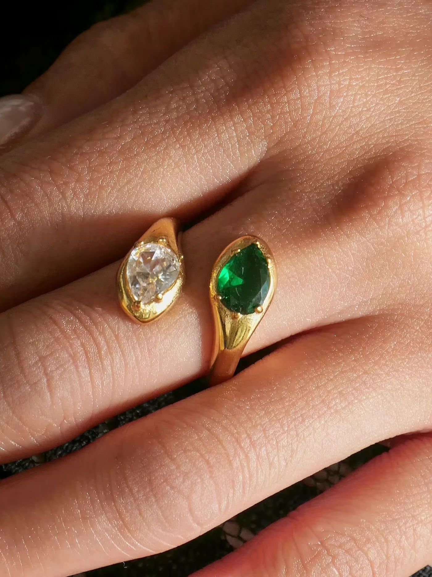 Gold patrica ring with green gemstone on a finger