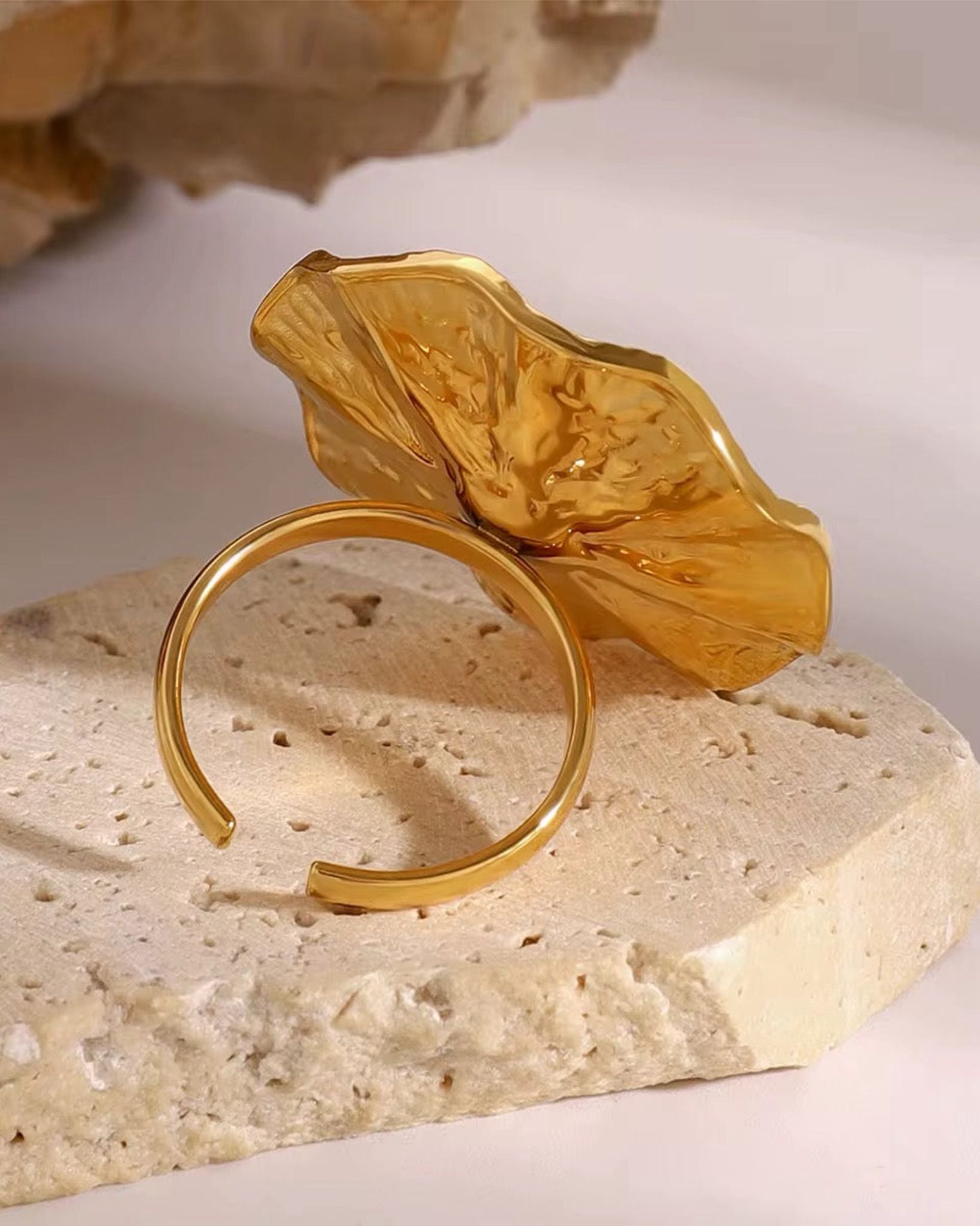 Gold pearl orbit ring with a leaf design on a stone surface