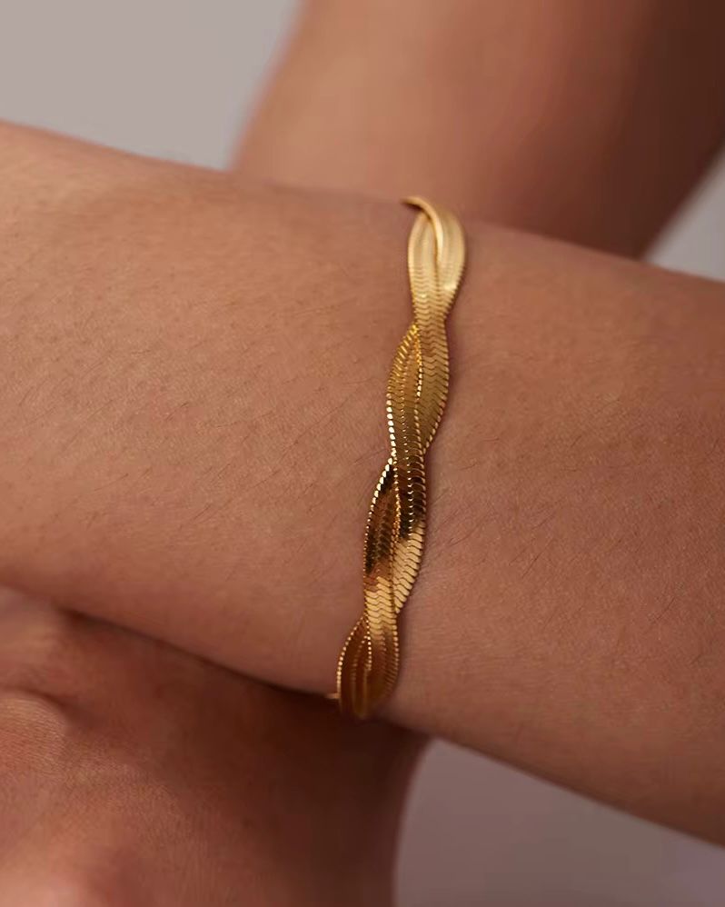 Gold bracelet on a wrist with a neutral background
