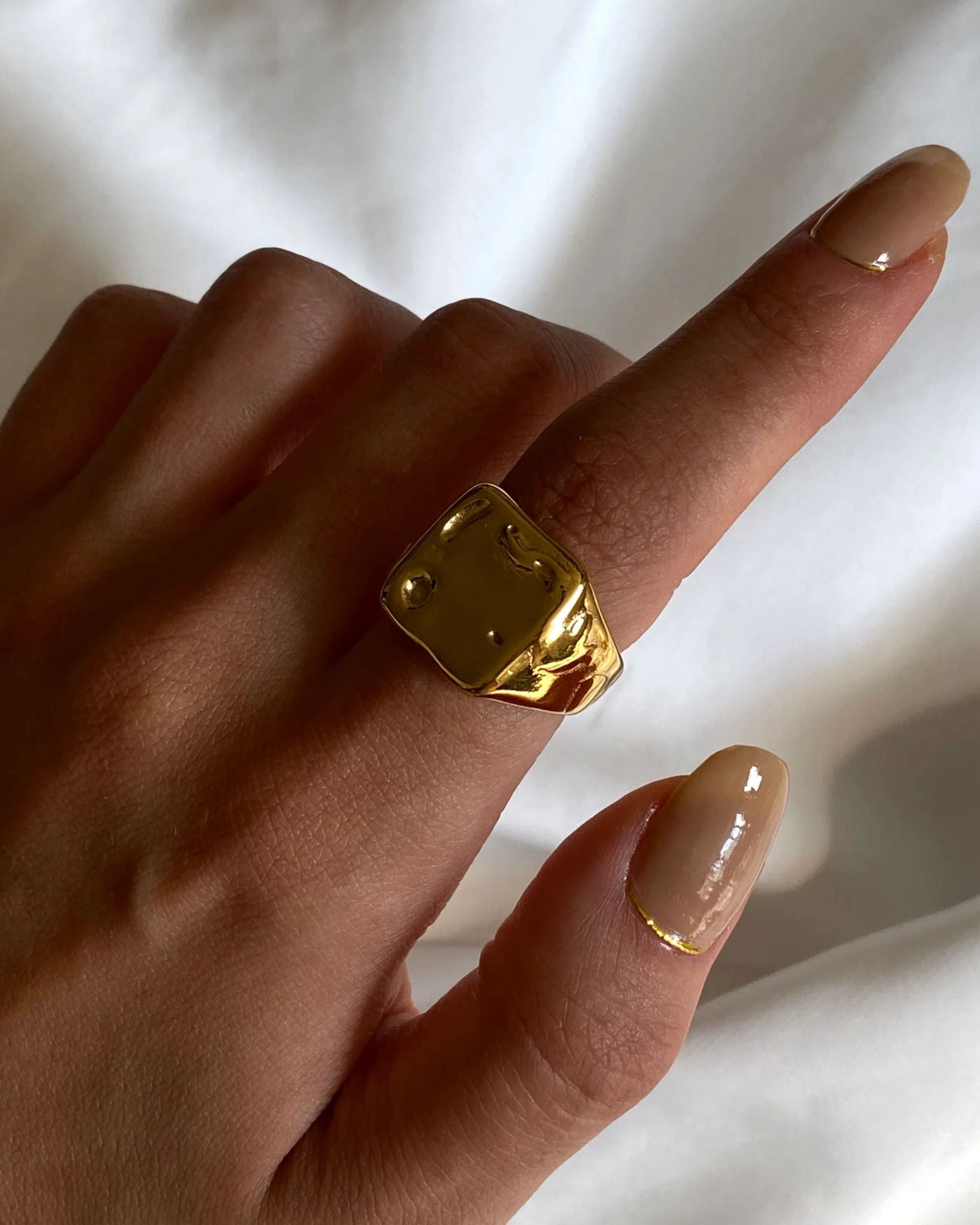 Gold ring on a finger with a blurred white background