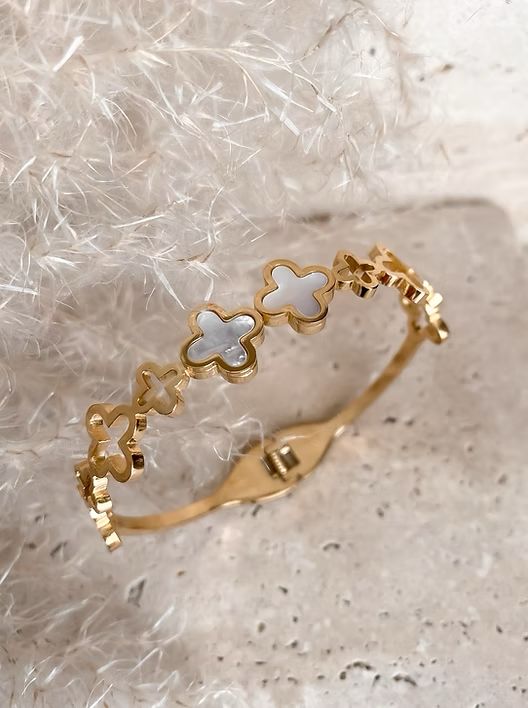 A gold-plated stainless steel lisa clover bangle bracelet with a magnetic closure, featuring a series of clover-shaped embellishments.