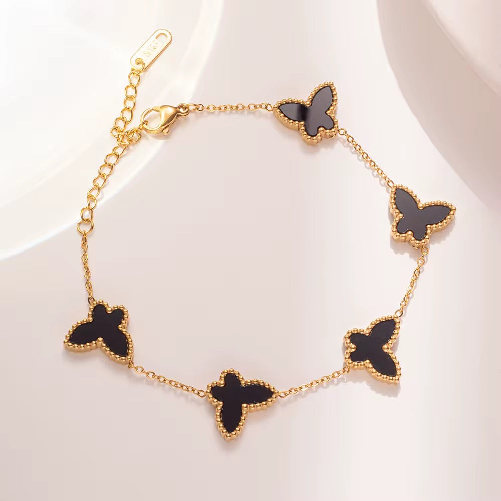 Gold bracelet with black butterfly charms on a white background