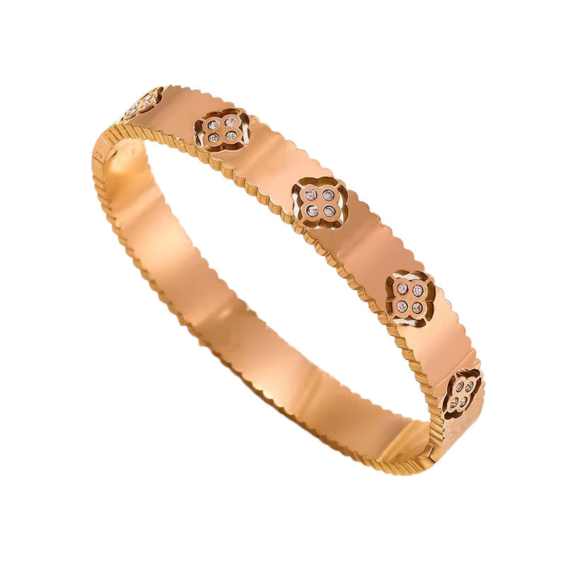 A rose gold theodora clover bangle bracelet with clover shaped embellishments and cubic zirconia accents, displayed against a white background.