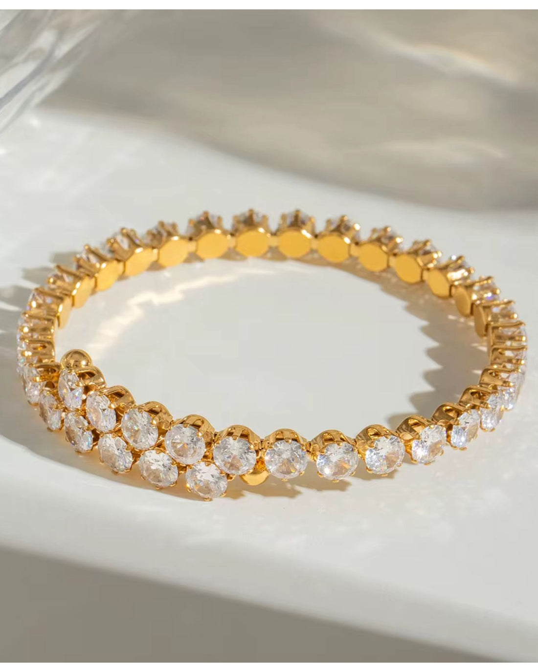 Gold bracelet with clear stones on a white surface
