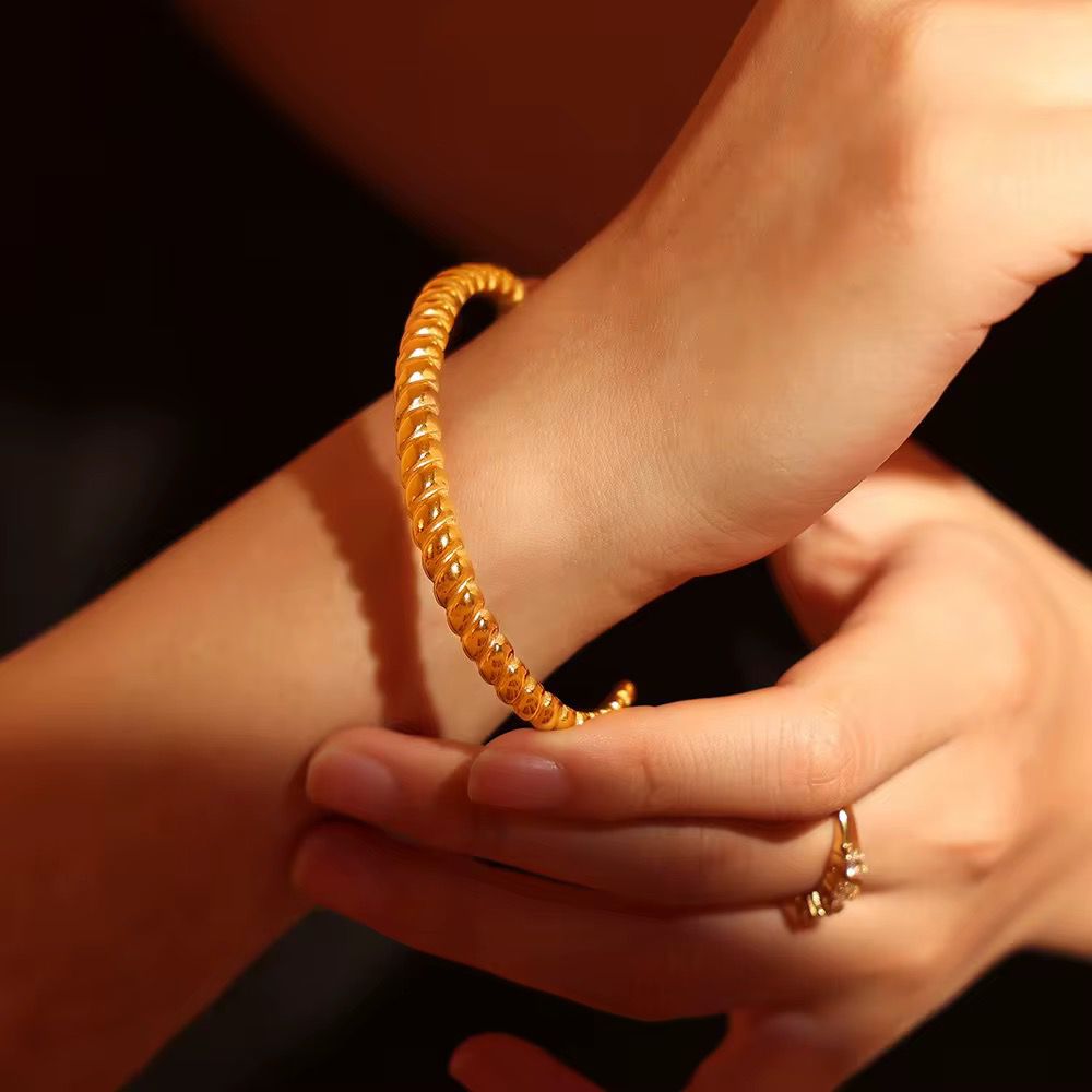 Close-up of a hand wearing a abstract gold bangle with a blurred background