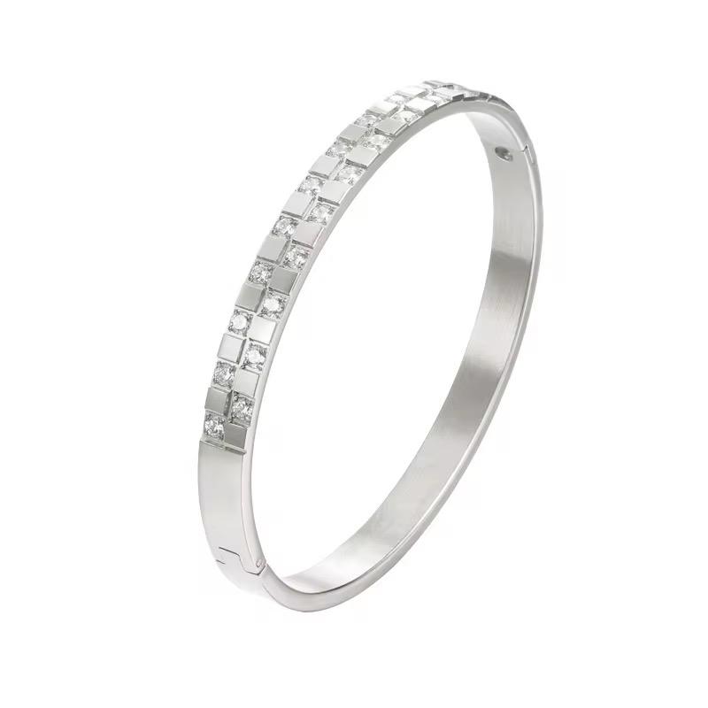 A silver bae bangle bracelet with a patterned surface, displayed against a white background.