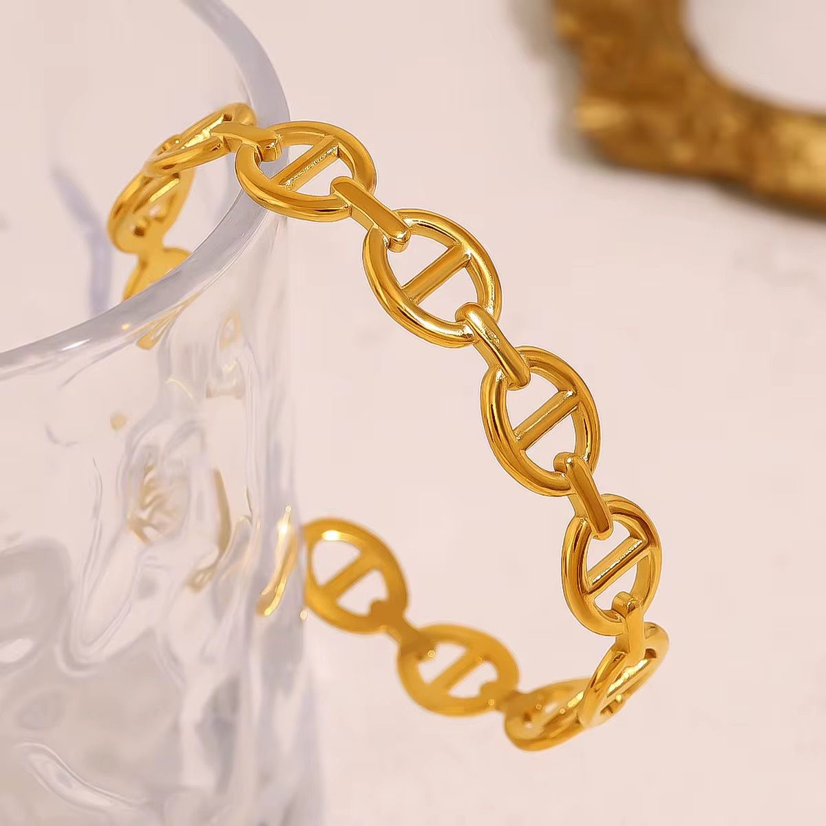 Gold oval chain bracelet with DNA symbol design on a white background