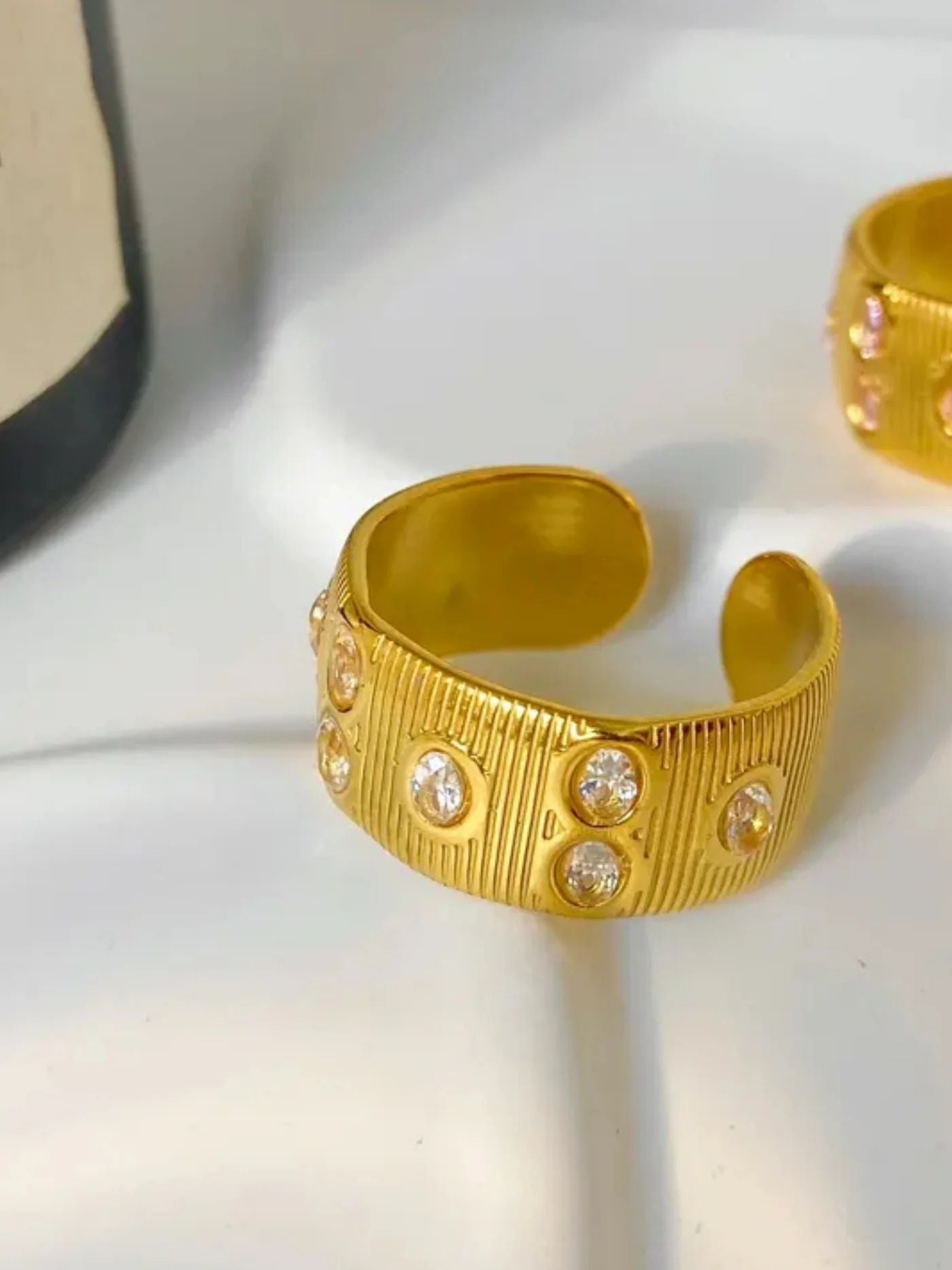 Gold cleo ring with embedded stones on a white surface