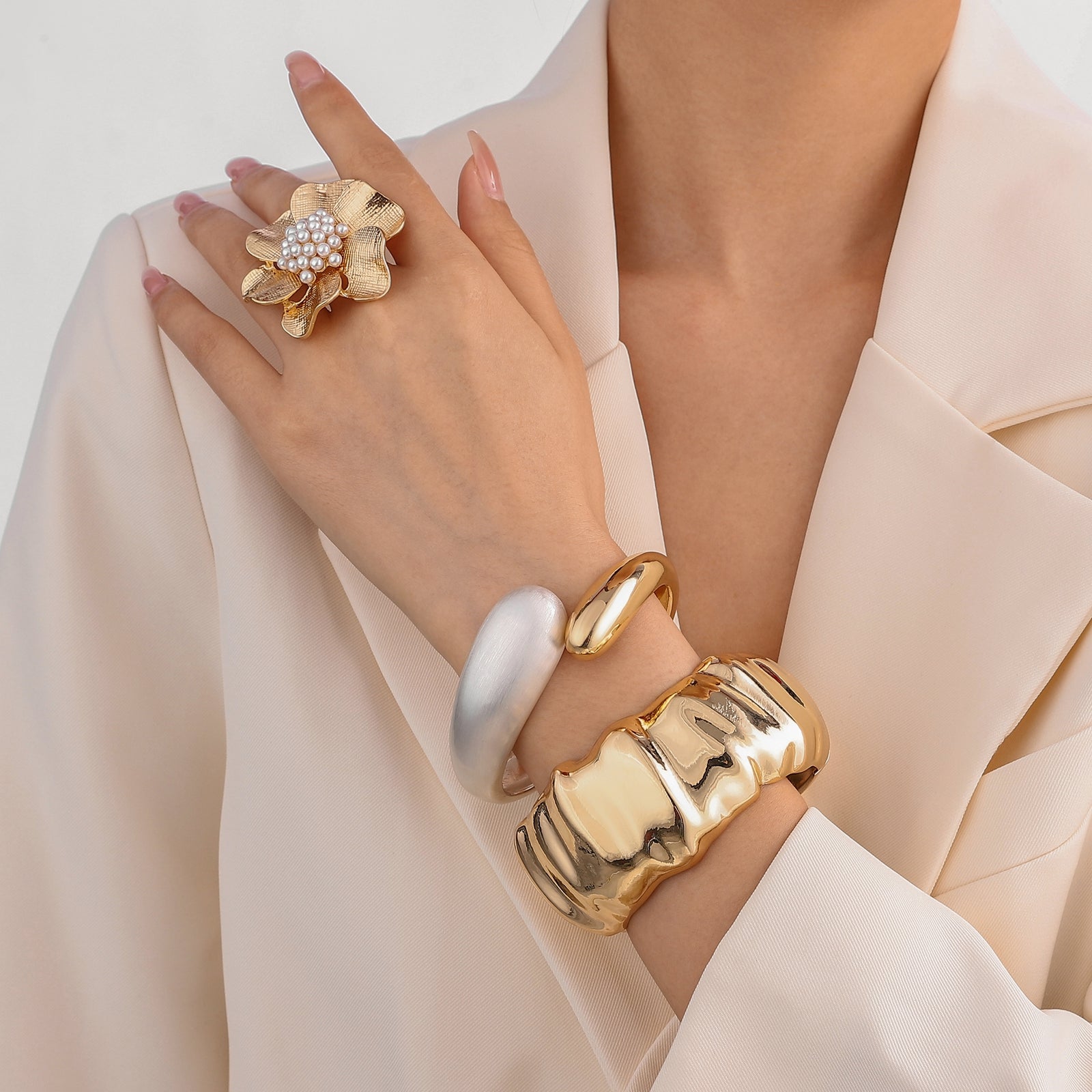 Gold jewellery including a emma pearl ring and bracelets on a neutral background