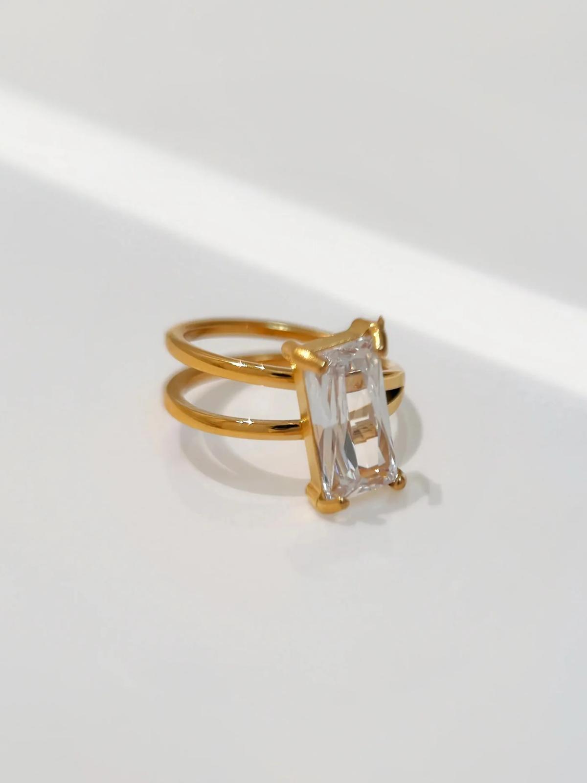 Gold freesia ring with a clear gemstone on a white background