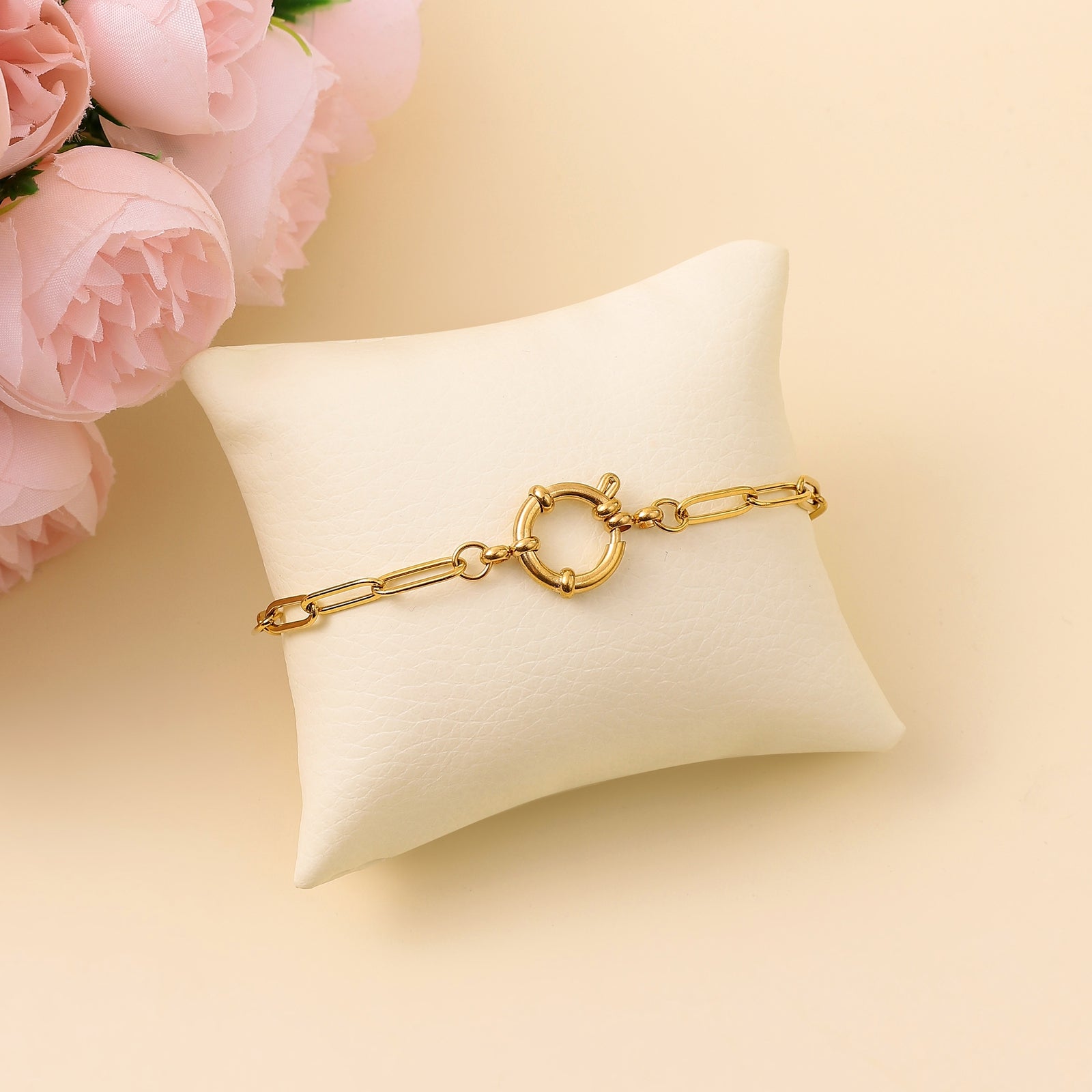 An 18k gold plated round bracelet displayed on a white cushion, featuring a block chain design.