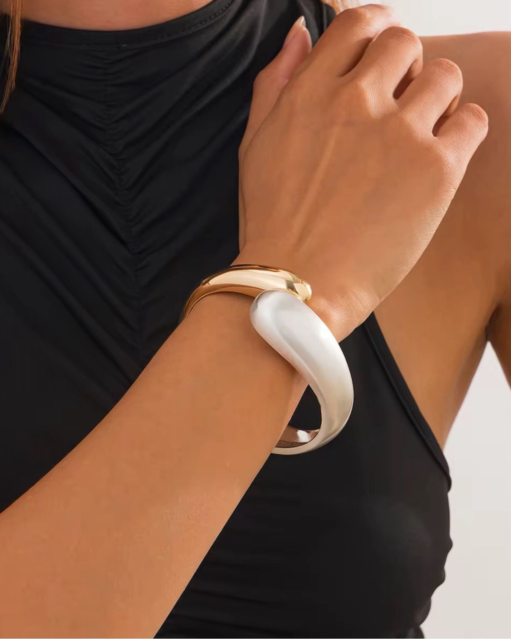 Close-up of a person wearing a white ignis cuff bracelet on a plain background