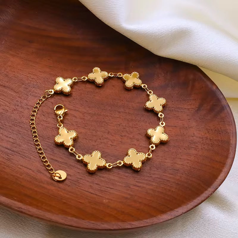 Gold louise clover bracelet with cross designs on a wooden surface.