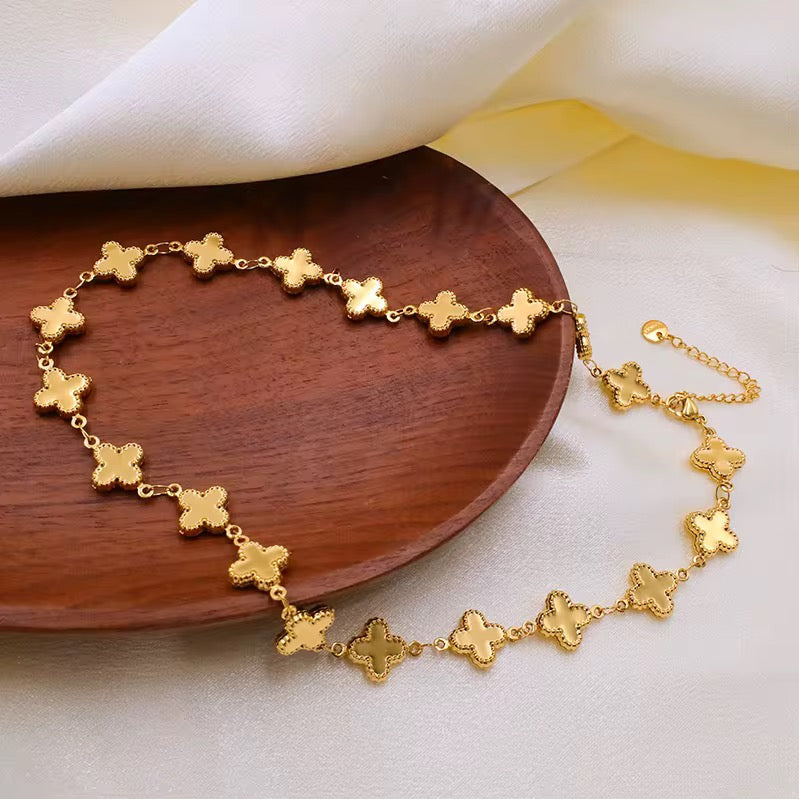 Gold louise clover bracelet with clover-shaped links on a wooden plate