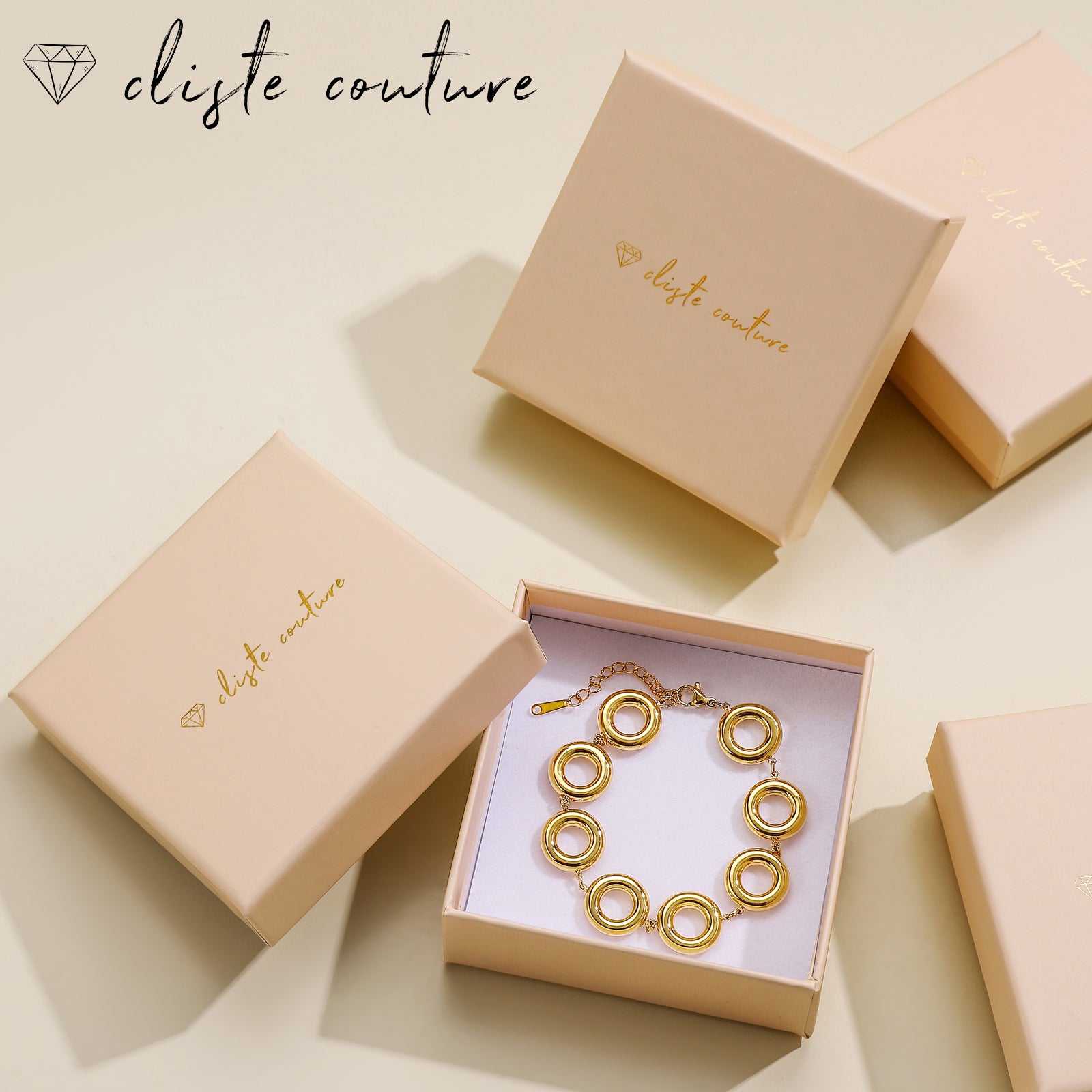 A gold cady set presented in a branded box, including a nyla clover bracelet and earrings with gold plating on a white background.
