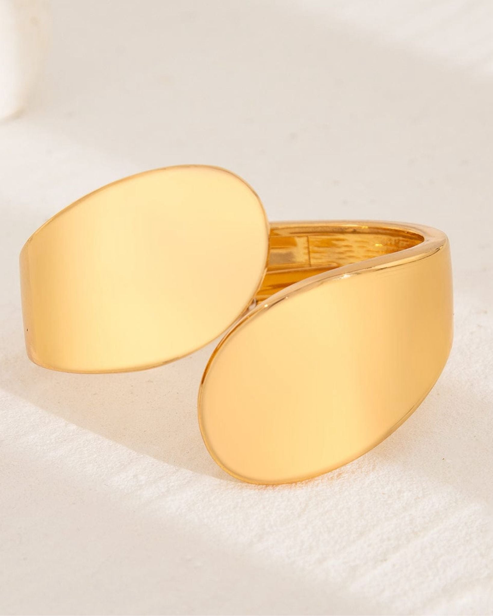 Gold ring with a smooth, oval-shaped design on a light beige background