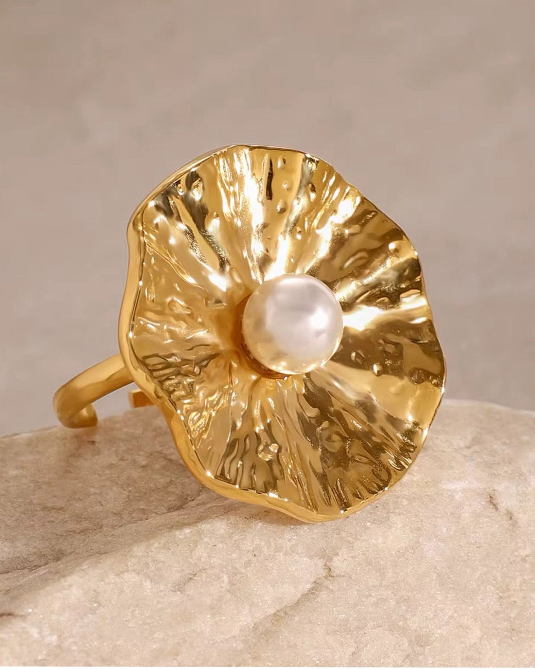 Gold pearl orbit ring with a pearl on a beige background