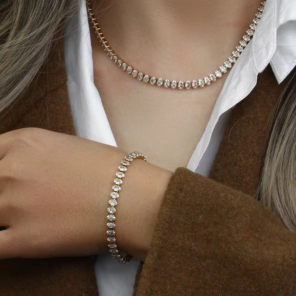 lady wearing a diamond rhinostone bangle and necklace with a white shirt and brown coat.