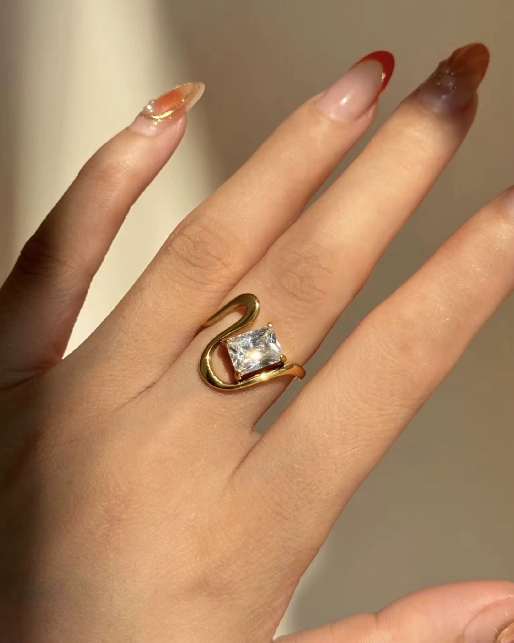 Gold ring with a diamond on a hand against a neutral background