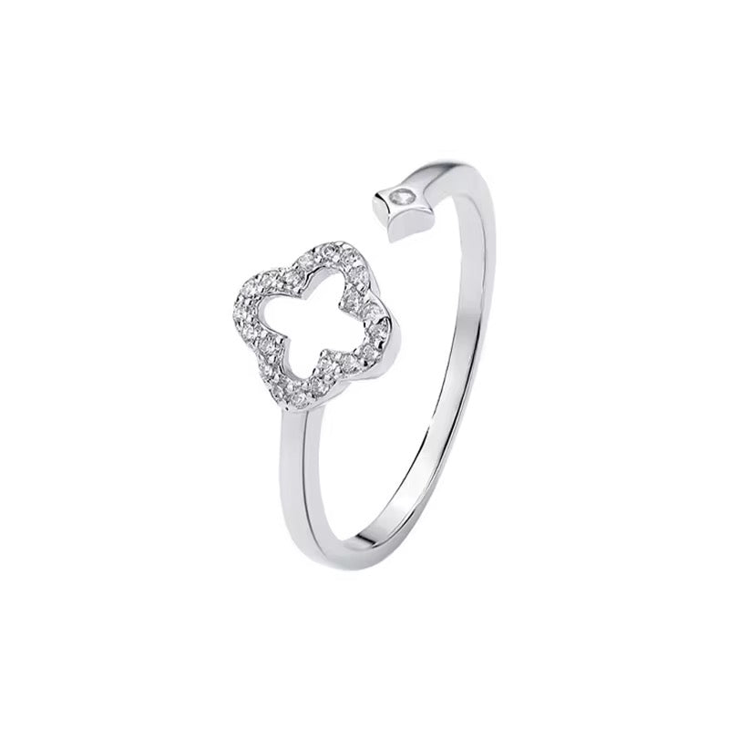 A sterling silver ring with a clover-shaped design adorned with zirconia stones, with an adjustable band.