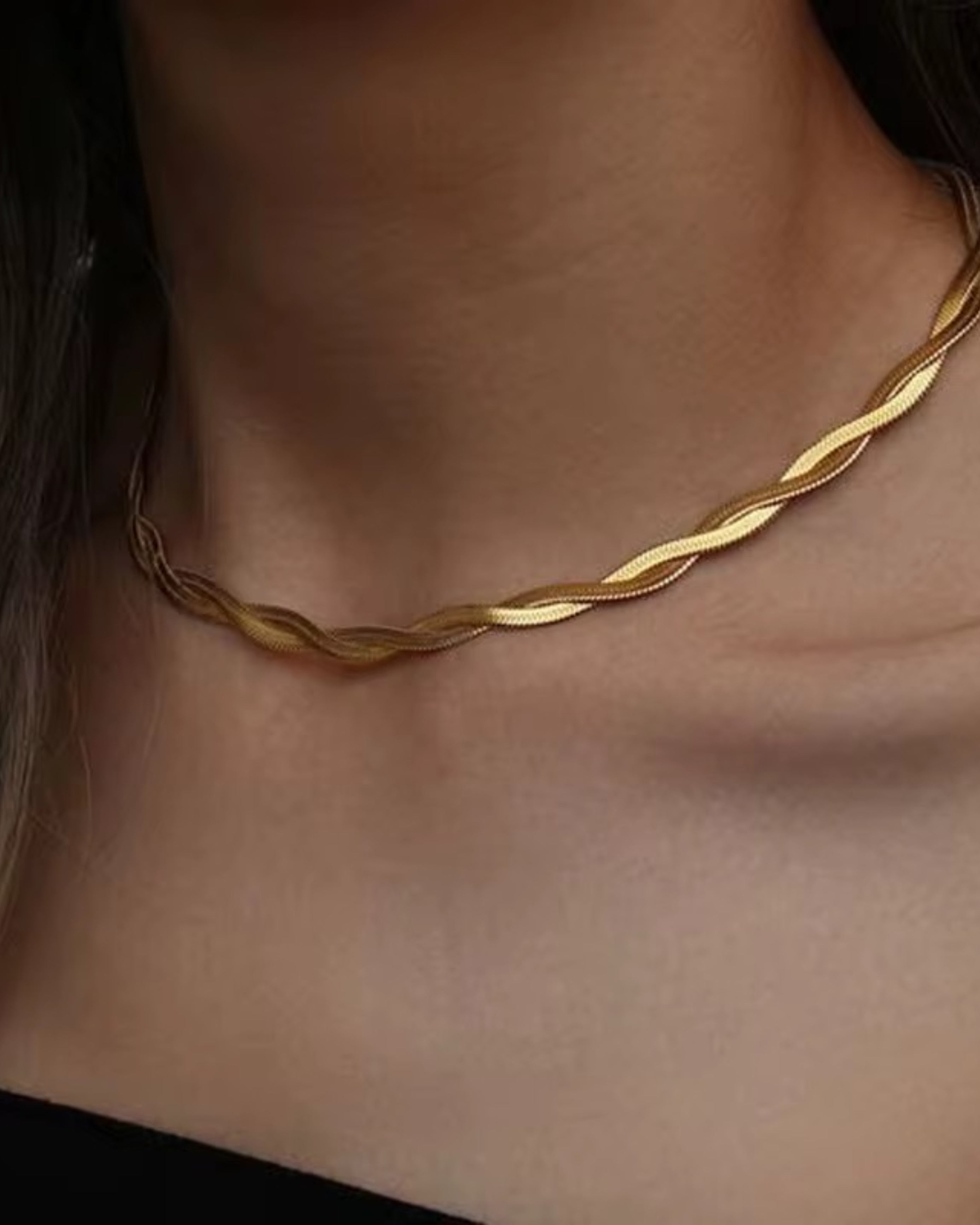 Gold twisted snake chain necklace on a person's neck