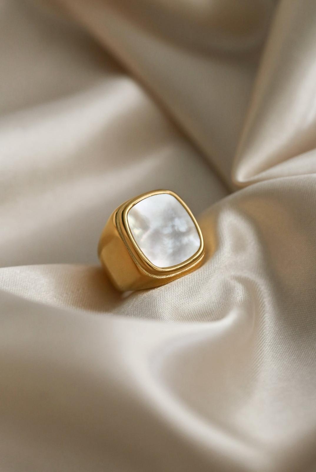 Gold white shell ring with a white stone on beige fabric