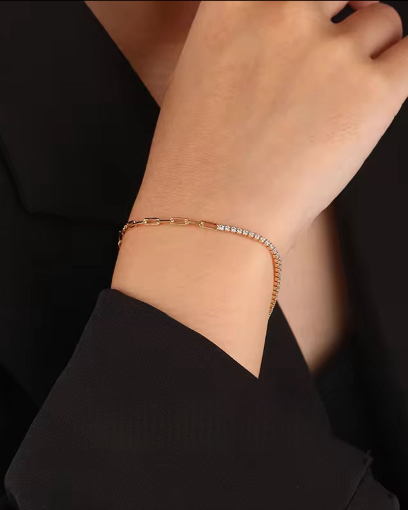 Gold zircon paper-clip bracelet on a wrist with a black background